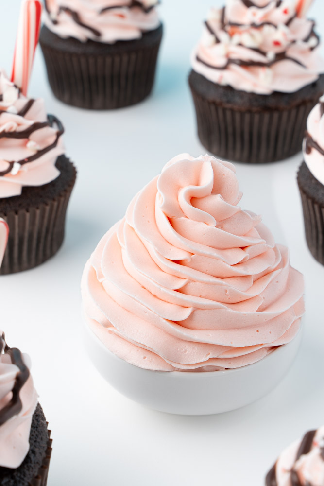 A swirl of candy cane buttercream frosting in a small white bowl.