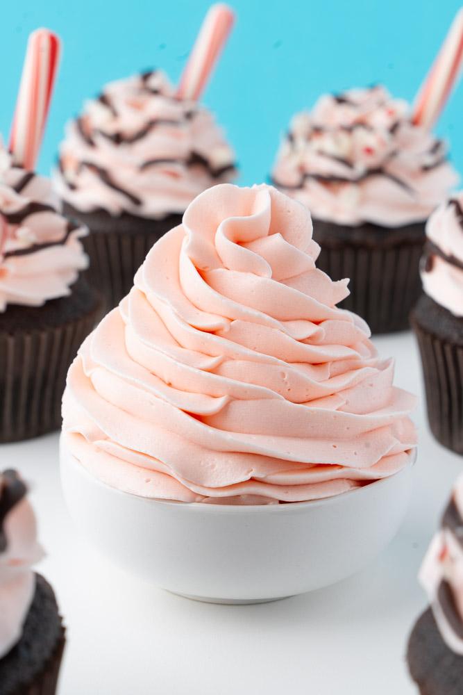 A swirl of candy cane buttercream frosting in a small white bowl.