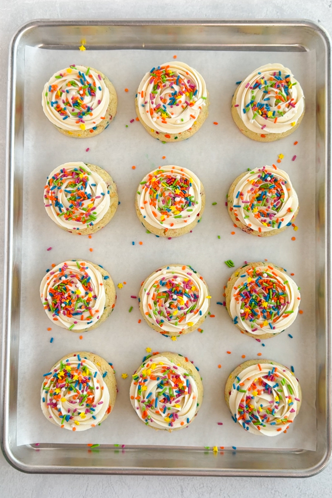 Cookies with vanilla frosting and rainbow sprinkles.