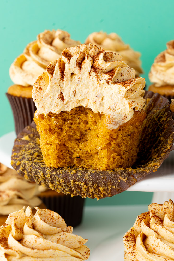A pumpkin cupcake with a bite taken out to show the interior of the cupcake.