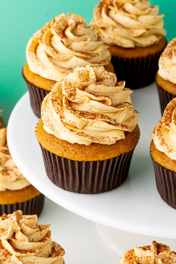 Easy pumpkin cupcakes with pumpkin spice frosting and cinnamon on a cake stand.