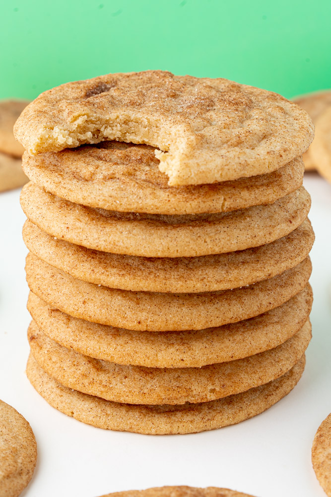 A stack of brown butter snickerdoodle cookies with a bite taken out of the top cookie to show the interior.