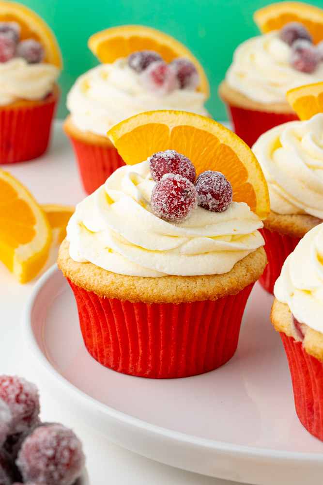 Orange cranberry cupcakes on a white plate.