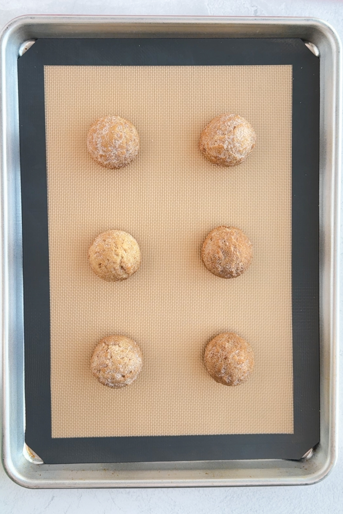 Cinnamon sugar cookie dough balls on a baking sheet pan.