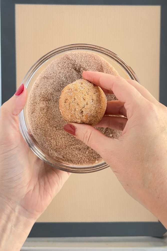 Rolling cookie dough balls in cinnamon sugar.