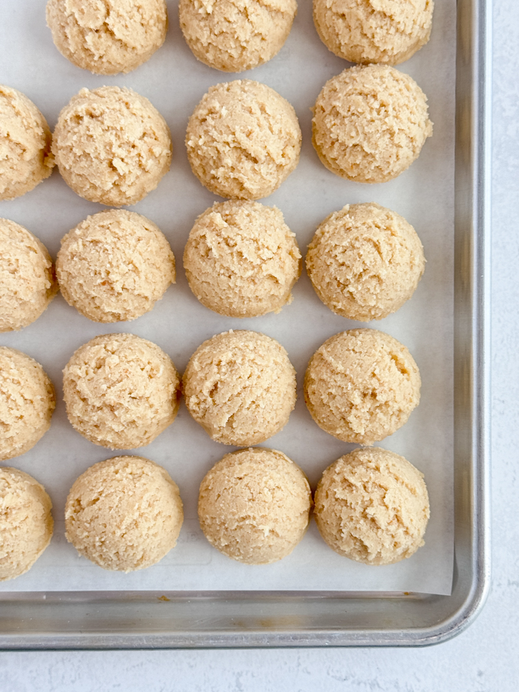 Scooped cookie dough on a baking sheet pan.