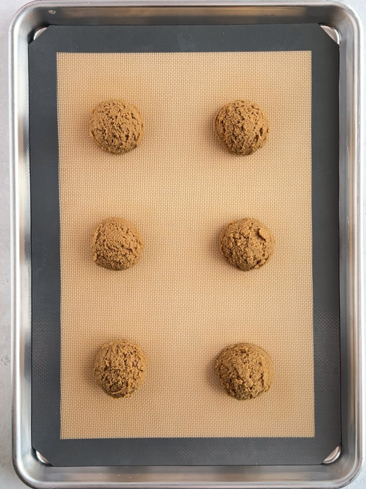 Gingerbread cookie dough balls on a baking sheet pan.