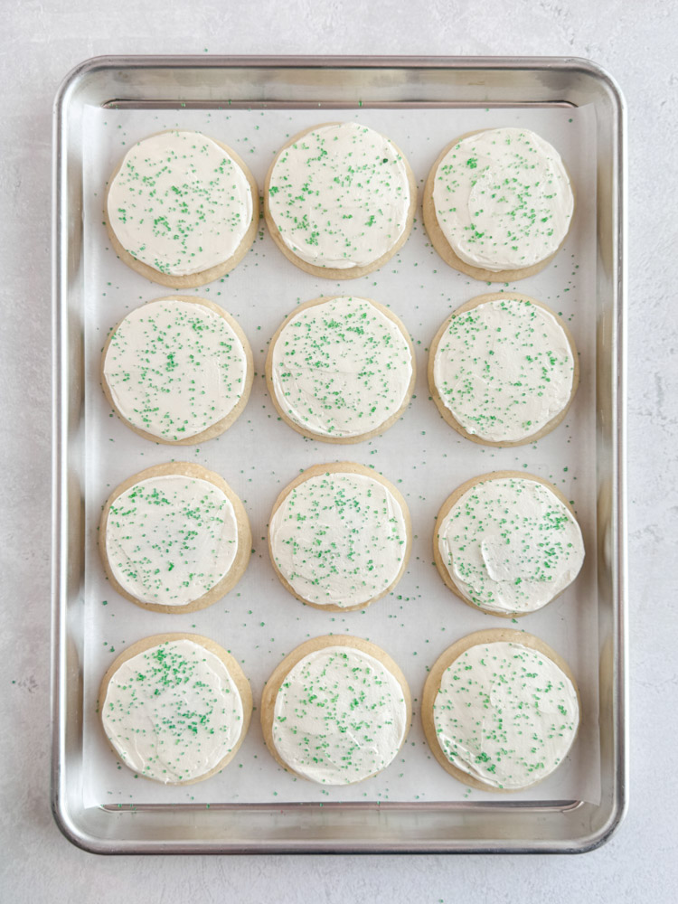 Vanilla cookies frosted with vanilla buttercream frosting and decorated with green sanding sugar.