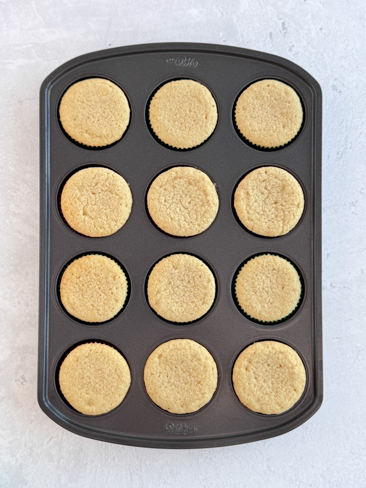 Baked vanilla cupcakes in a cupcake pan.