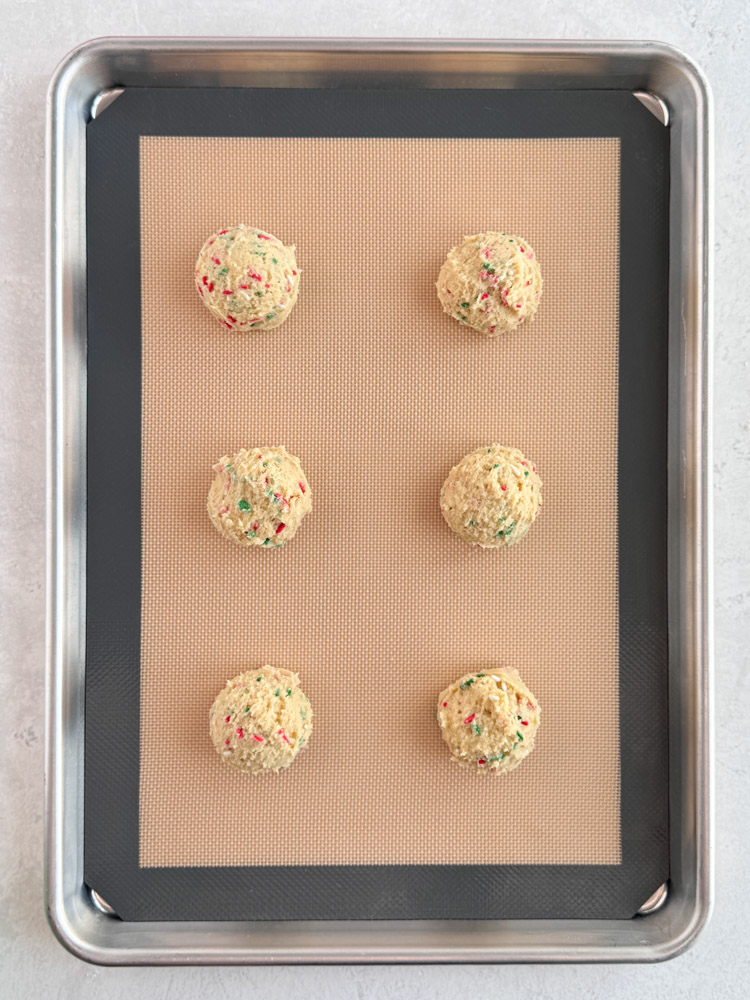Chilled sugar cookie dough balls on a baking sheet pan.