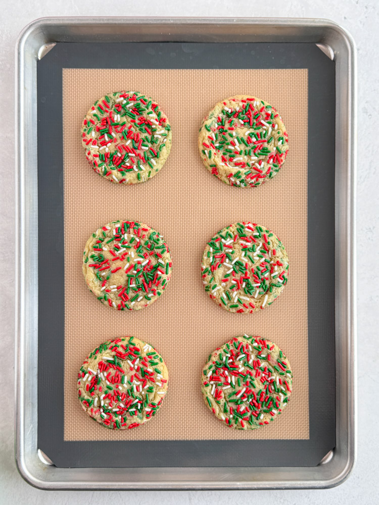Baked sprinkle cookies on a baking sheet pan.