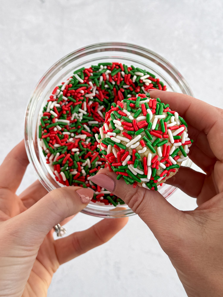 A scooped cookie dough ball covered in Christmas sprinkles.