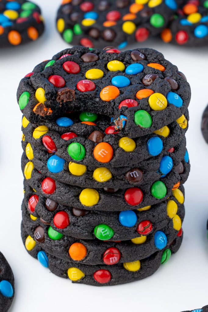 A bite taken out of a chocolate M&M cookie to show the chewy interior texture.