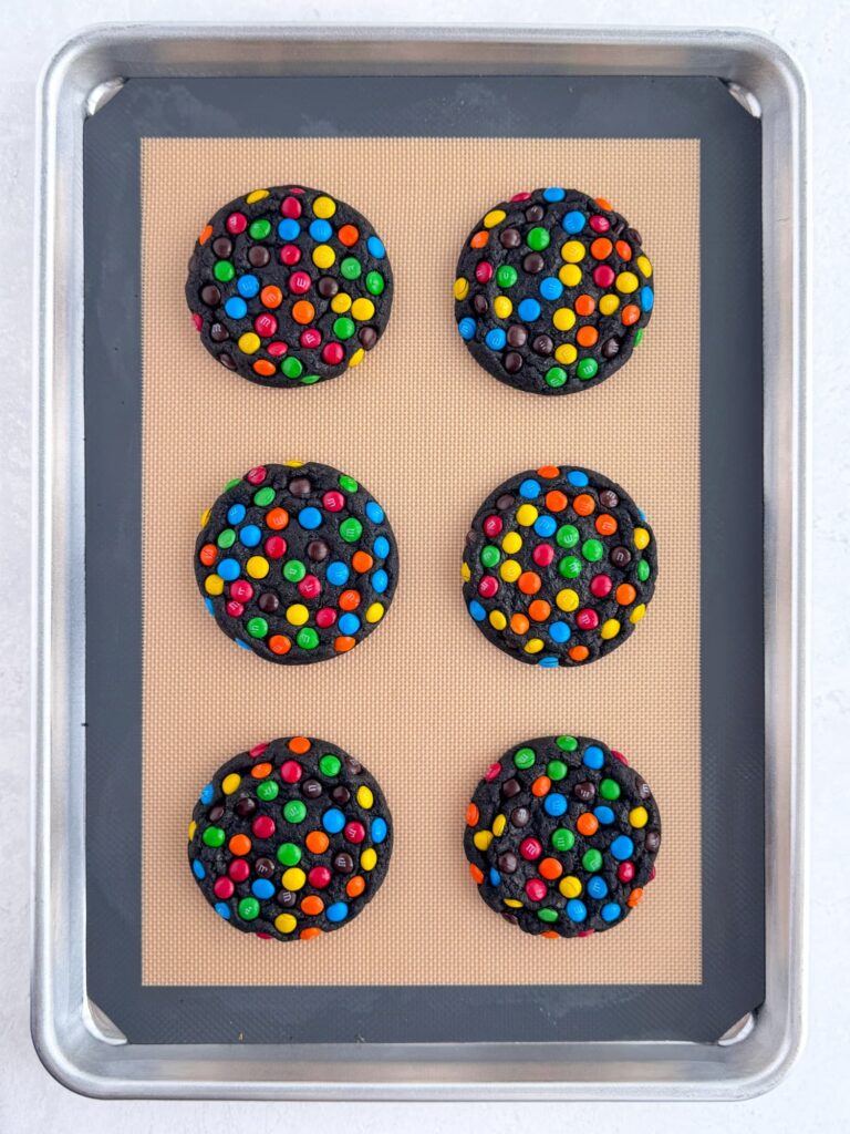 Baked chocolate M&M cookies on a baking sheet pan.