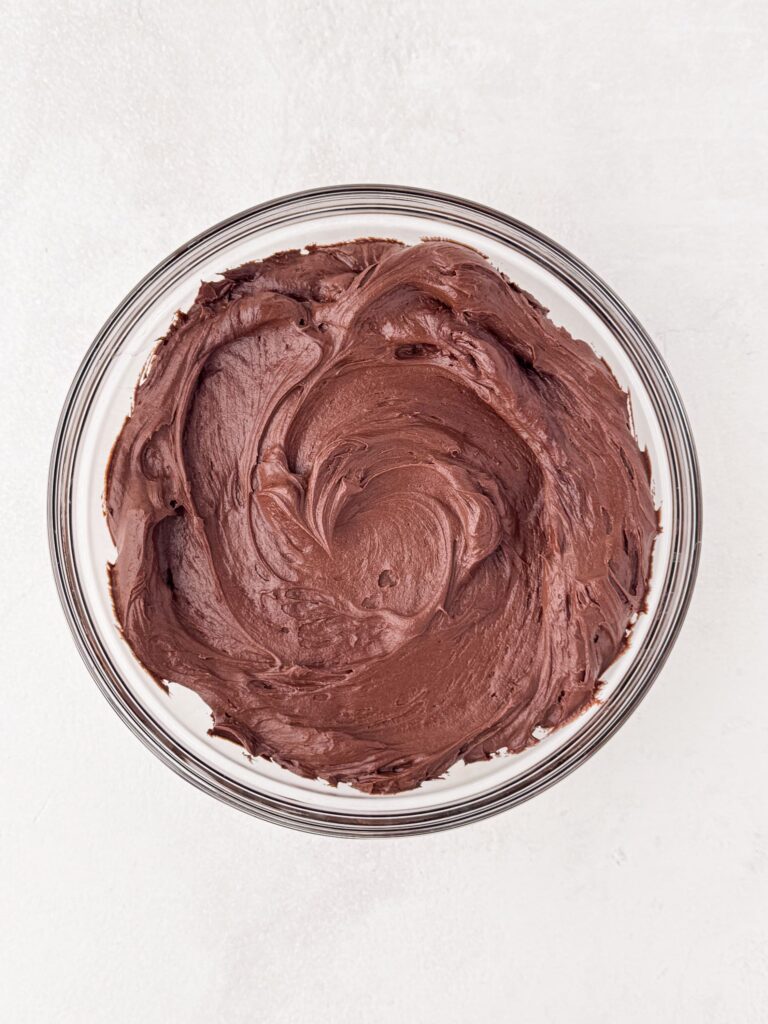 Chocolate buttercream frosting in a glass bowl.