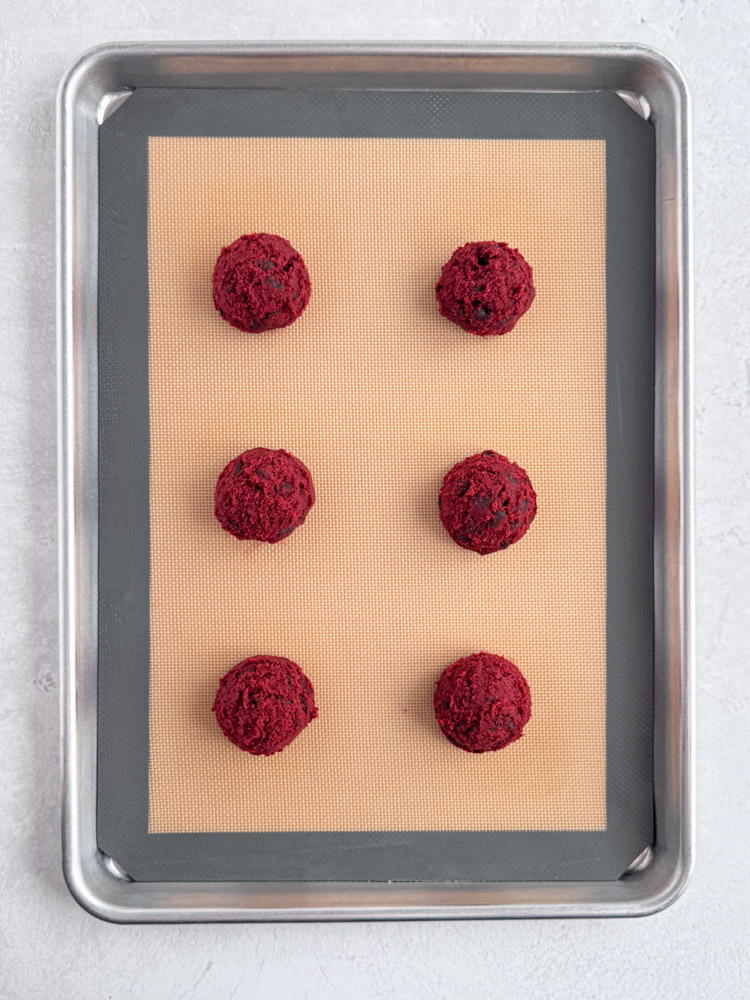 Cookie dough balls on a baking sheet pan.