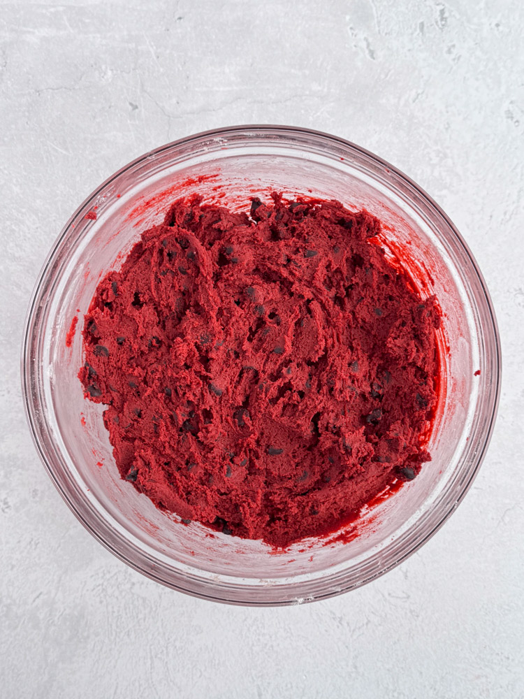 Red velvet chocolate chip cookie dough in a glass bowl.