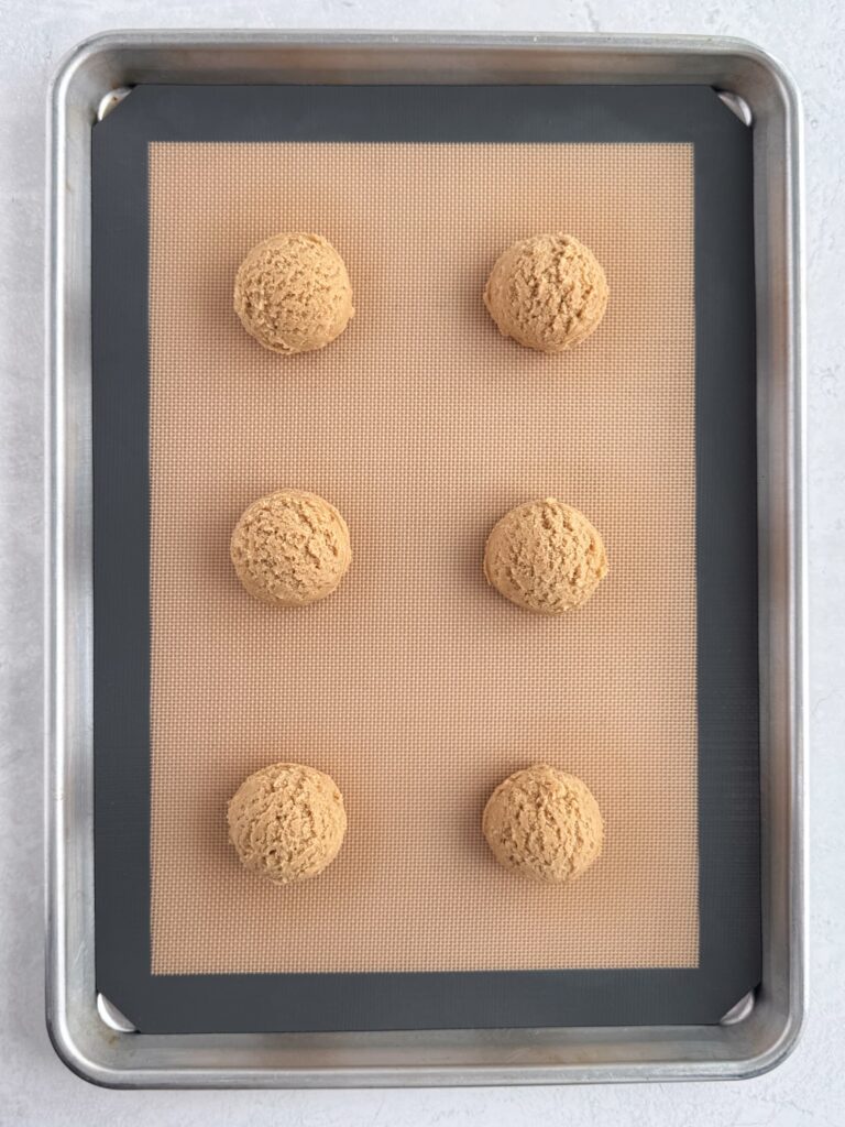 Cookie dough balls on a prepared baking sheet pan.