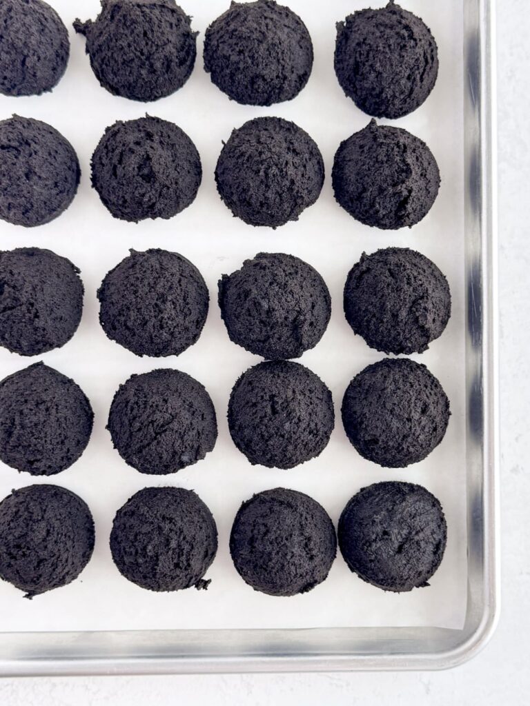 Chocolate cookie dough balls on a parchment-lined baking pan.