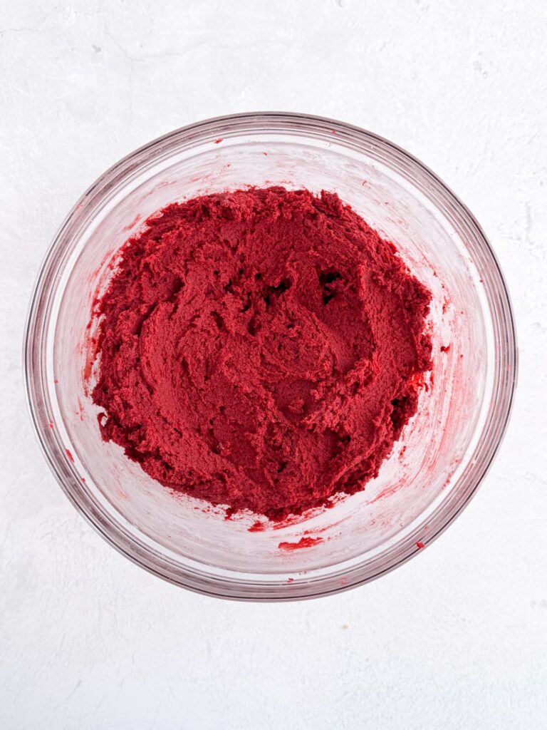 Red velvet cookie dough in a glass mixing bowl.