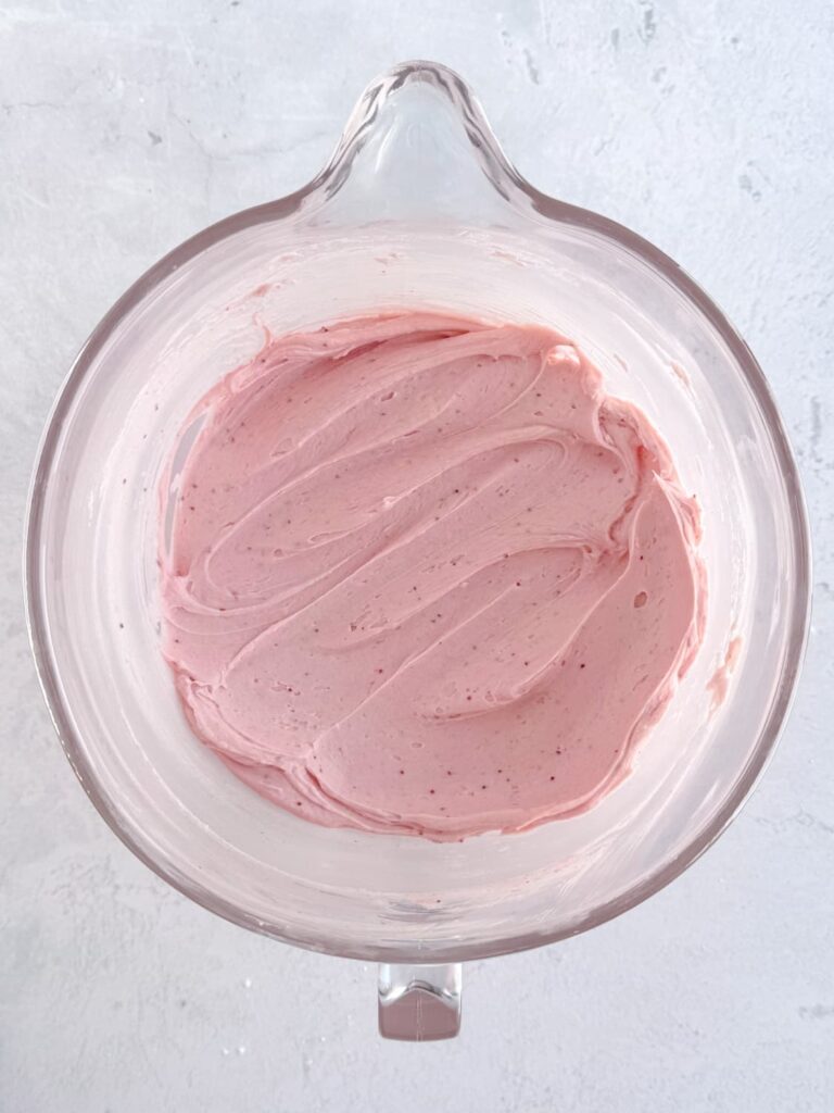 Strawberry buttercream frosting in a glass mixing bowl.