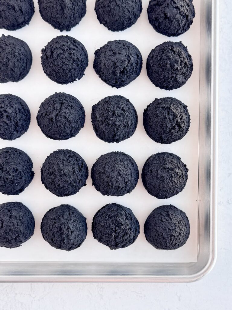 Chocolate cookie dough balls on a parchment lined baking pan.