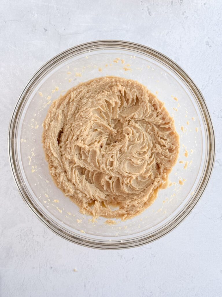 Whipped butter, sugar, and eggs in a glass mixing bowl.