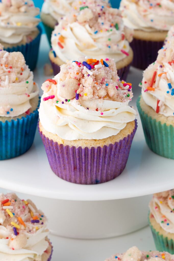 Birthday cake cupcakes on a white cake stand.