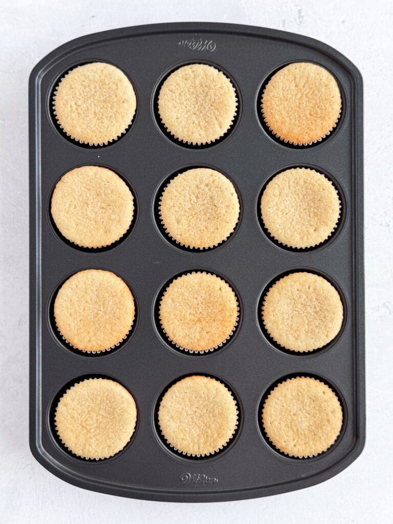 Baked vanilla almond cupcakes in a cupcake pan.