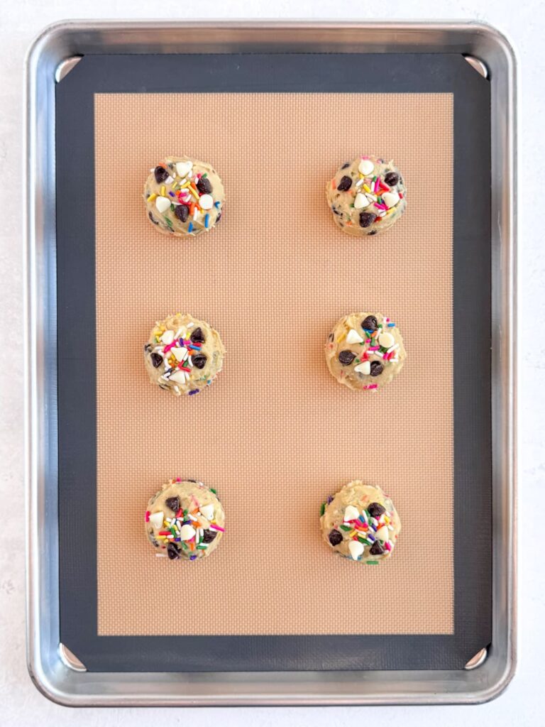 Cookie dough balls on a baking sheet pan.