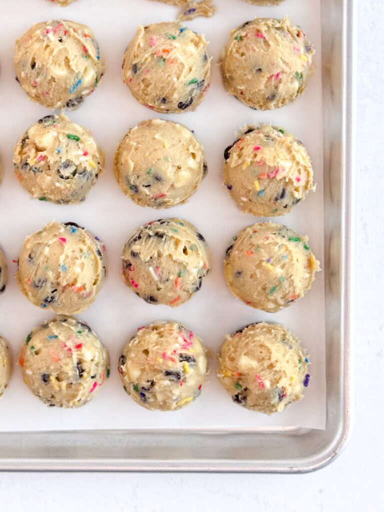 Scooped cake batter chocolate chip cookie dough on a baking sheet pan.