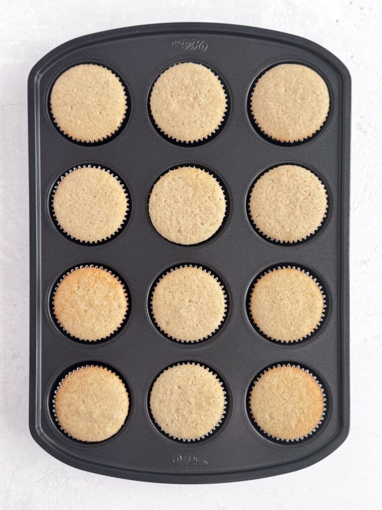 Baked vanilla bean cupcakes in a baking pan.