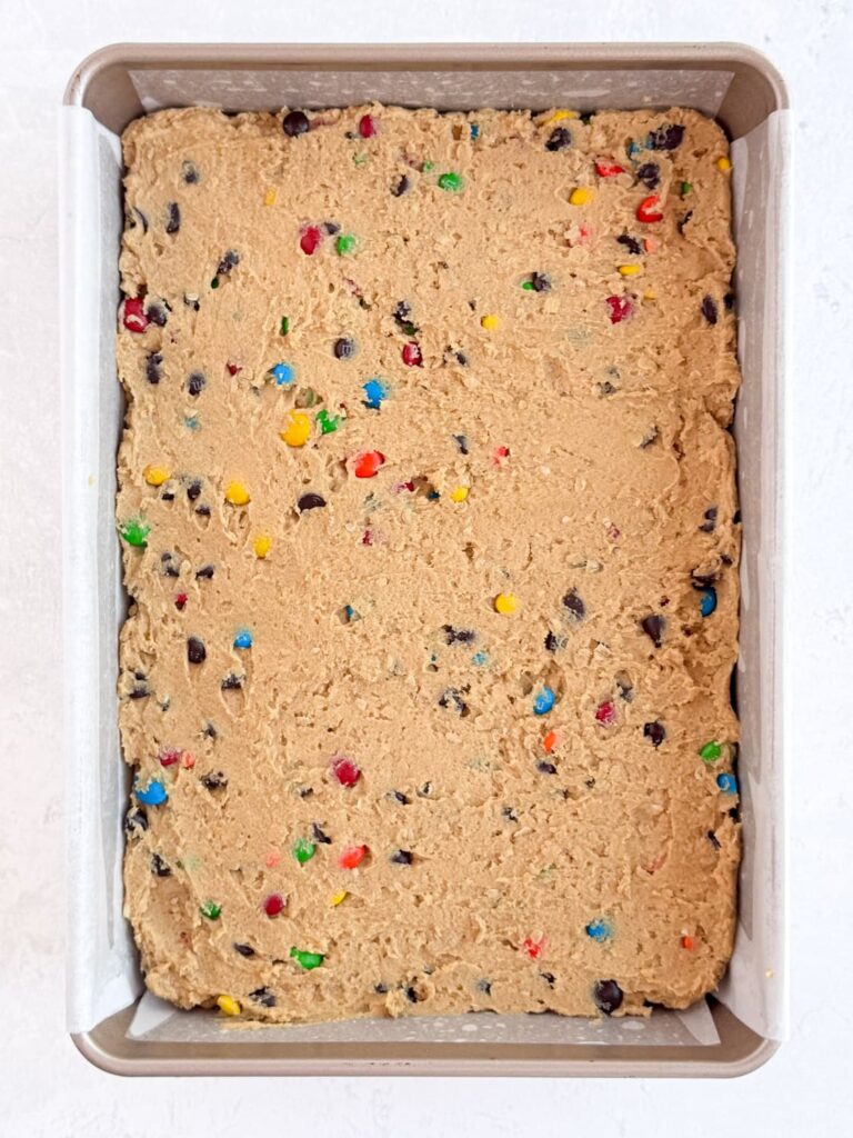 Monster cookie dough pressed into a prepared baking pan.