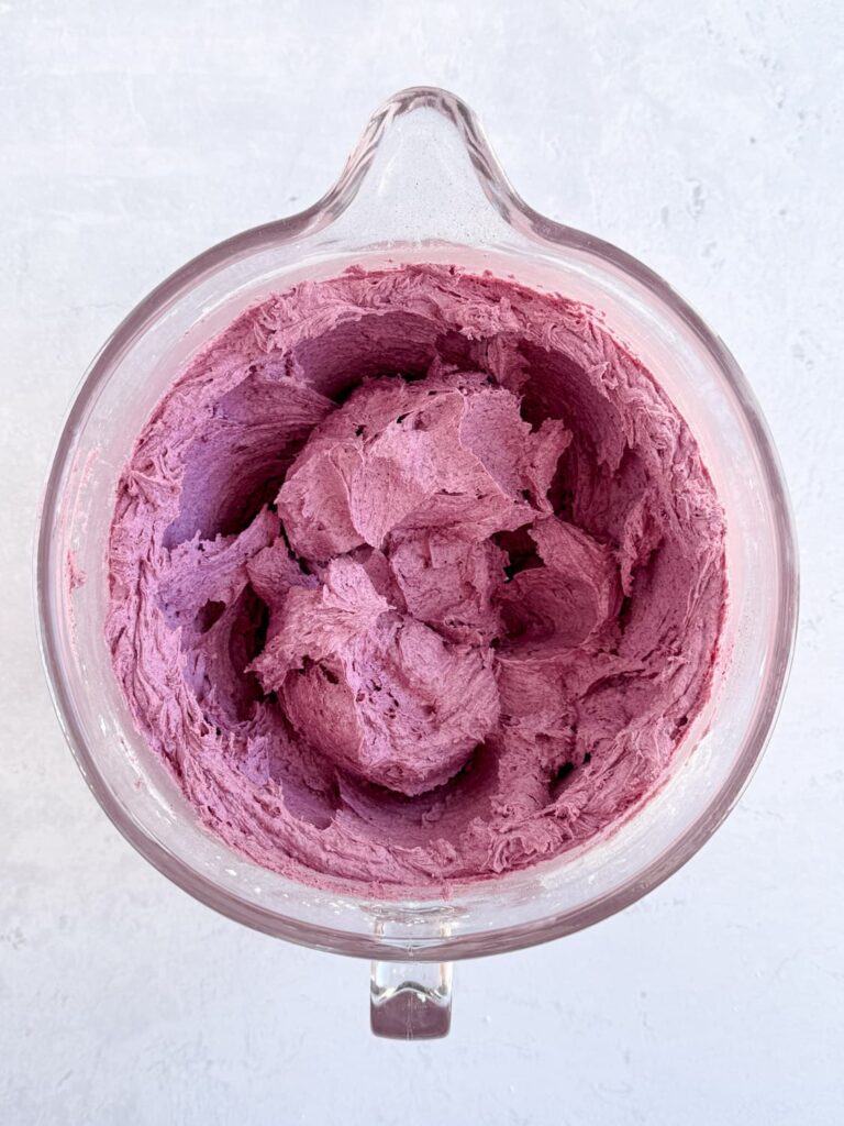 Blueberry powder mixed into frosting in a mixing bowl.