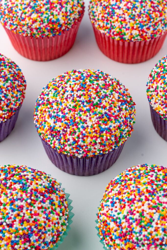 Vanilla cupcakes with rainbow nonpareil sprinkles.