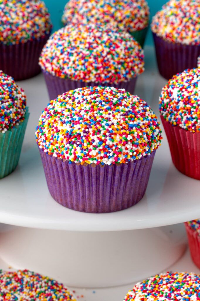 Colorful dot cupcakes on a white cake stand.