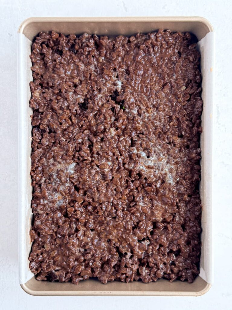 Chocolate Rice Krispie treat mixture spread and pressed into a baking pan.