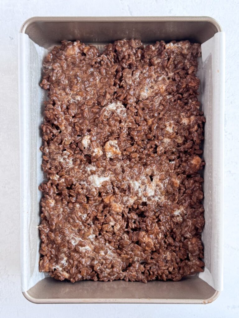 Chocolate Rice Krispie treat mixture spread into a baking pan.