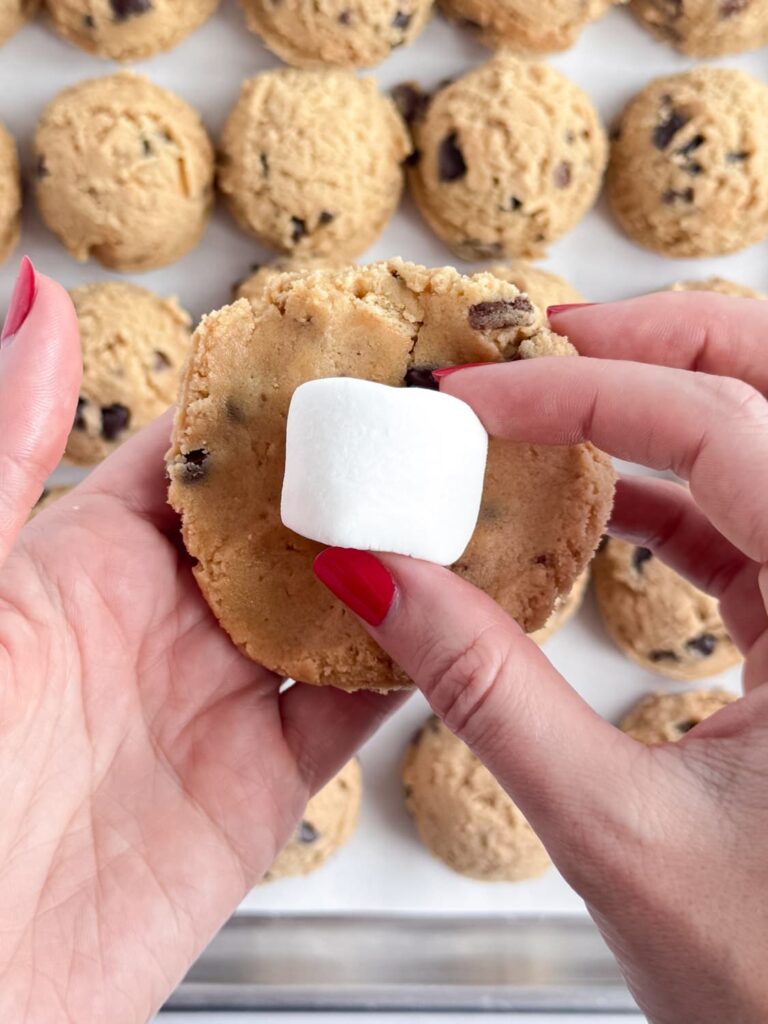 Flattened out cookie dough with a marshmallow in the center.