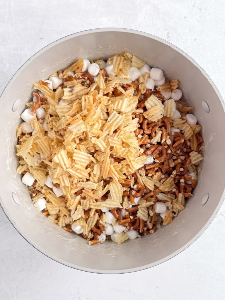 Potato chips, pretzels, and crisp rice cereal in a saucepan.
