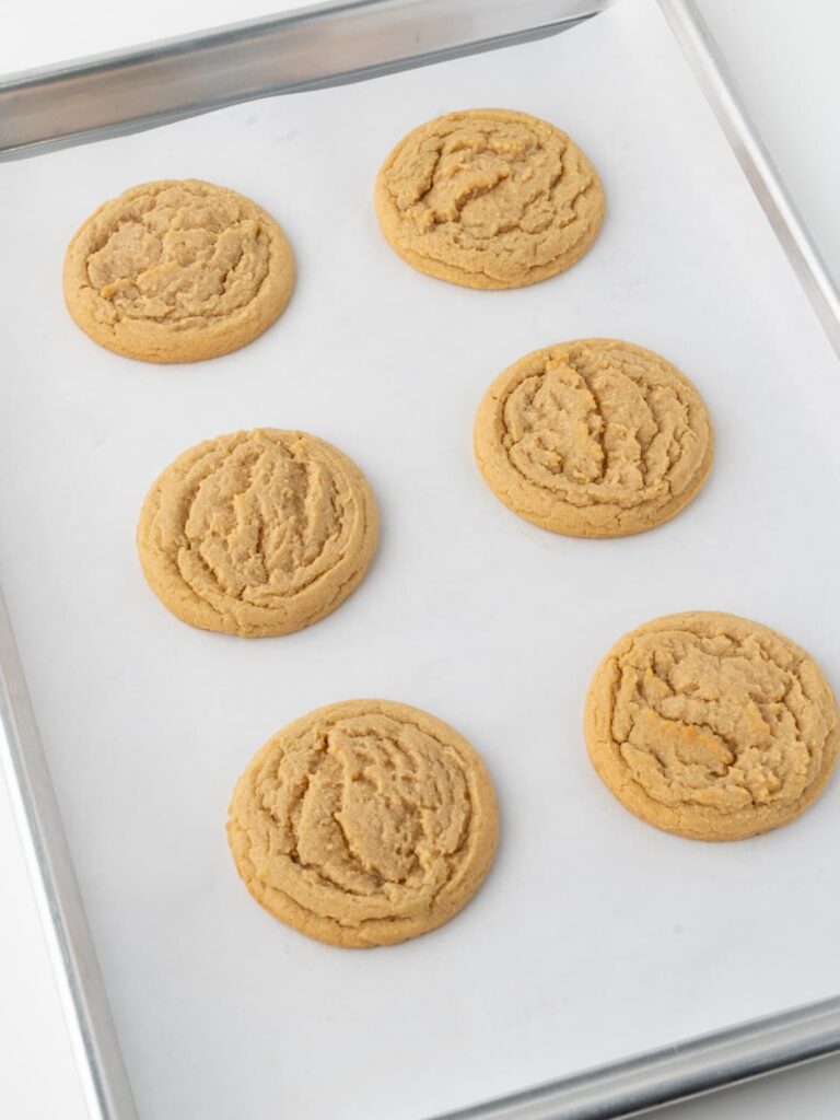 Baked peanut butter cookies on a baking sheet pan.
