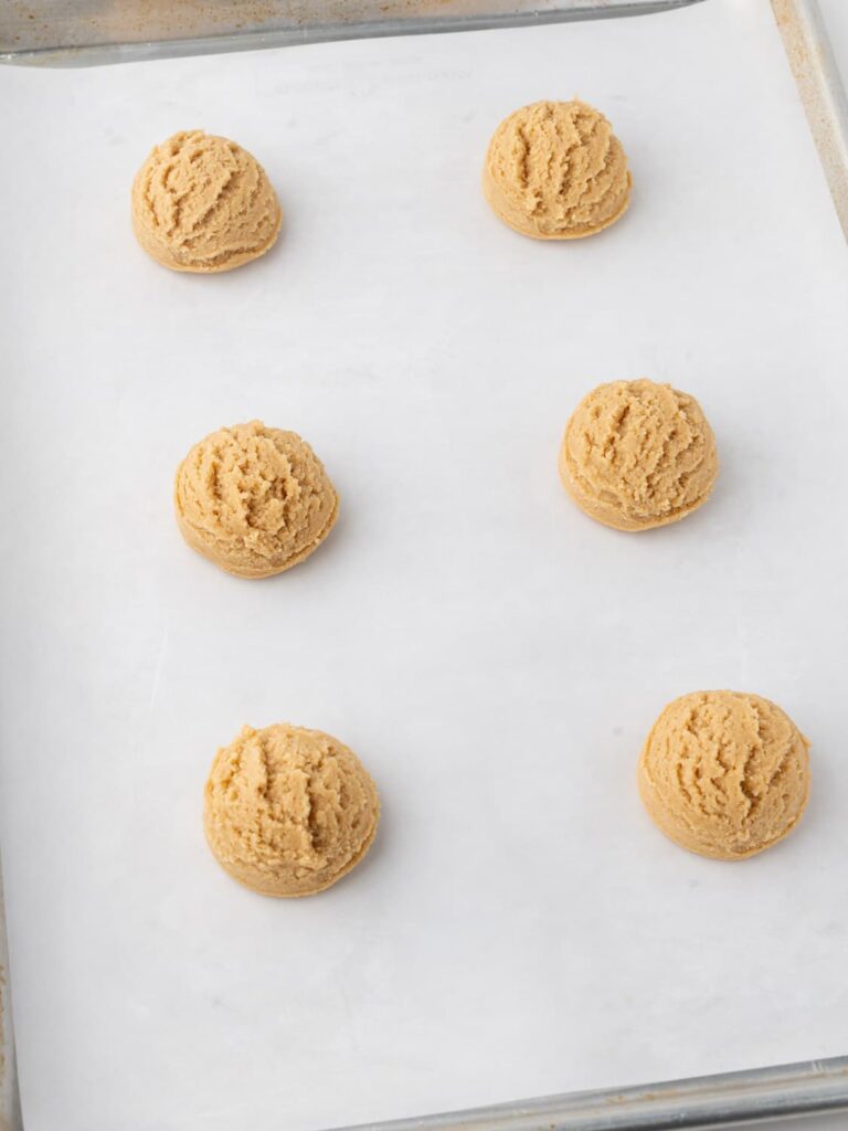 Peanut butter cookie dough balls on a baking sheet pan.