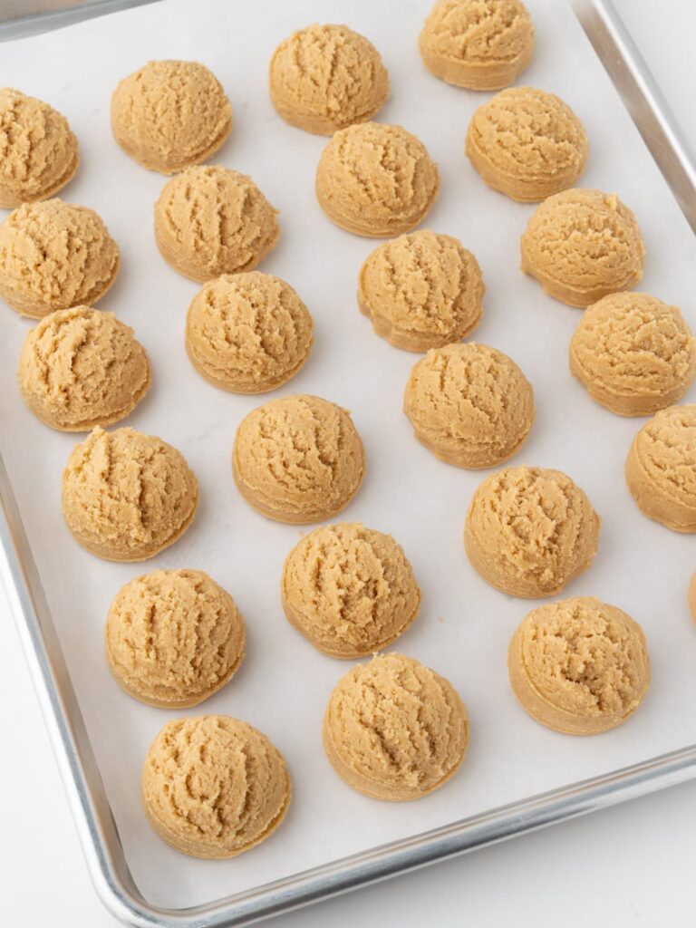 Peanut butter cookie dough balls on a baking sheet pan.