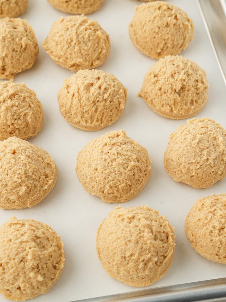 Cinnamon brown sugar cookie dough portioned into balls on a baking sheet before chilling.